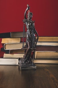 Statue Lady Justice on Wooden Table With Books Law Concept